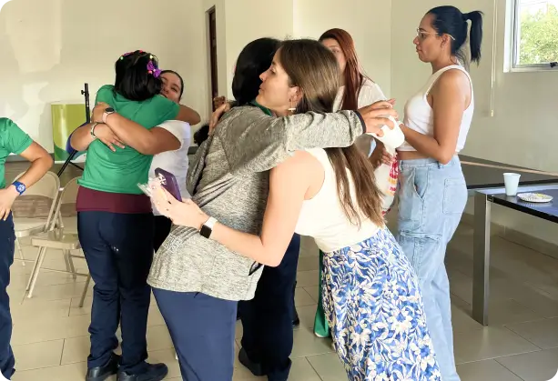 A group of women embracing in a cheerful atmosphere, demonstrating teamwork, support, and camaraderie within the SPECTRAFORCE workspace.