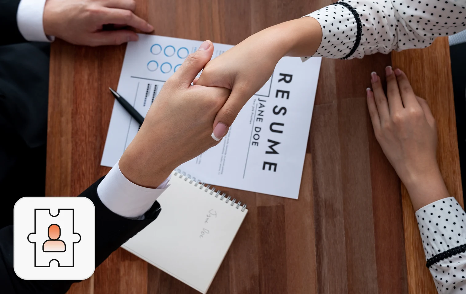 Staff augmentation concept: Two people seated across the table, shaking hands over a resume placed on the table